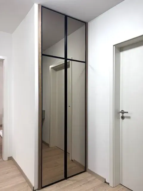 Spiegelschrank in einem Flur mit weißer Wand und Holzboden