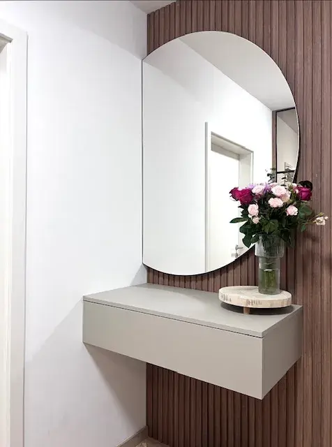 Moderner Flur mit rundem Spiegel, grauer Konsole und Vase mit rosa und roten Rosen.