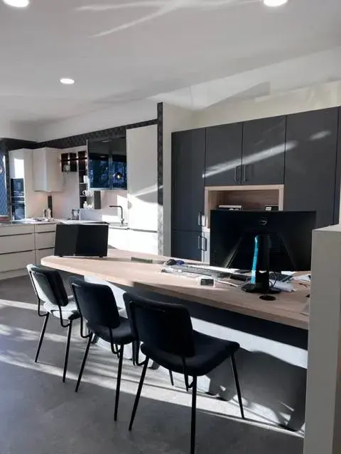 Modernes Büro mit Schreibtisch, drei Stühlen und Computer, viel Tageslicht.