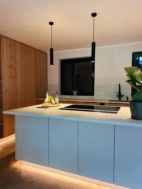 Moderne Küche mit Kochinsel, Holzschränken und indirekter Beleuchtung.