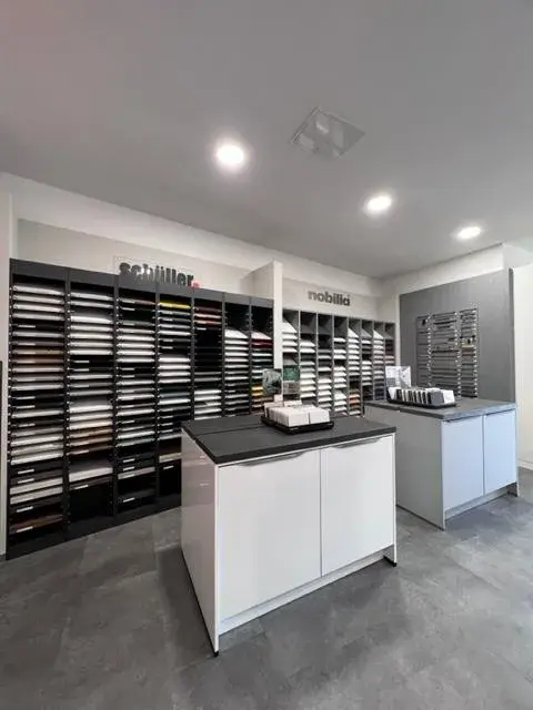 Moderne Musterraum mit Regalen voller Materialproben und zwei weißen Tischen.