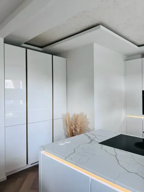 Moderne weiße Küche mit Kochinsel aus Marmor und dezentem LED-Licht.